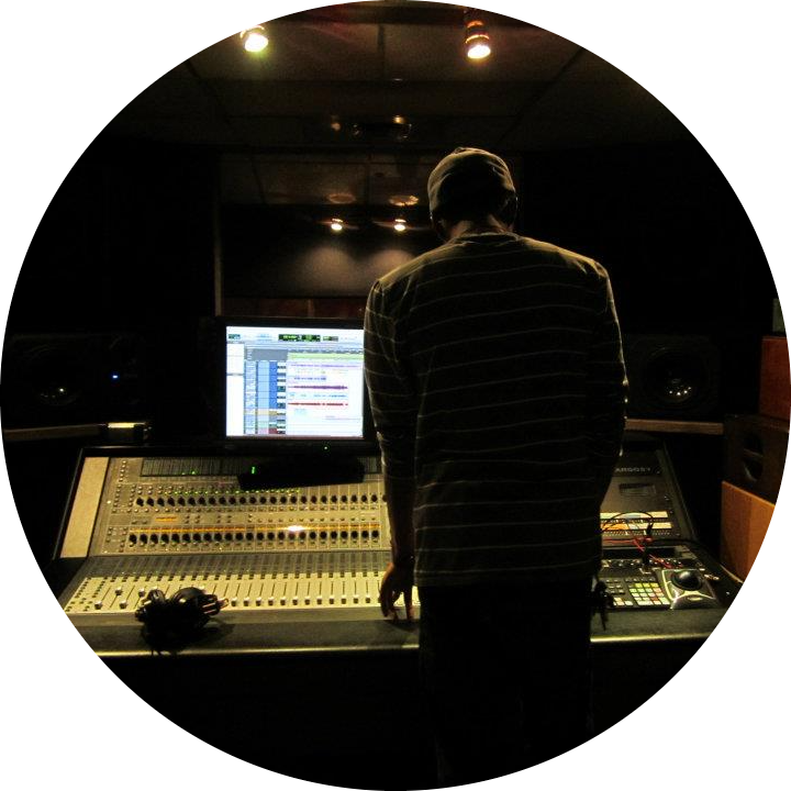 a music producer standing in front of a mixing board with Pro Tools on the computer screen